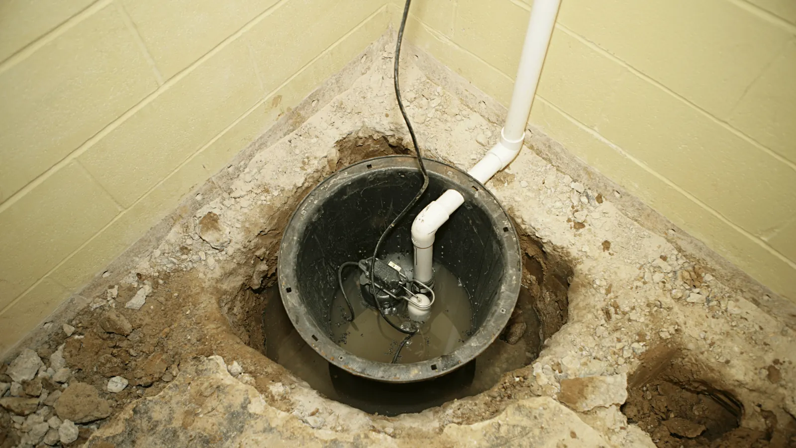 Sump pump installed inside a concrete floor basin pit